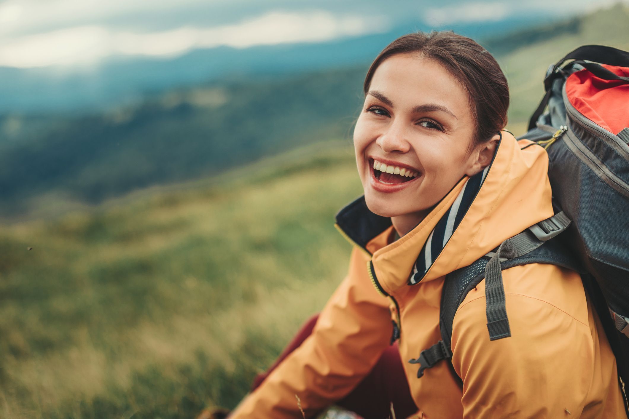 Smiling woman in a yellow jacket on a mountain trail
